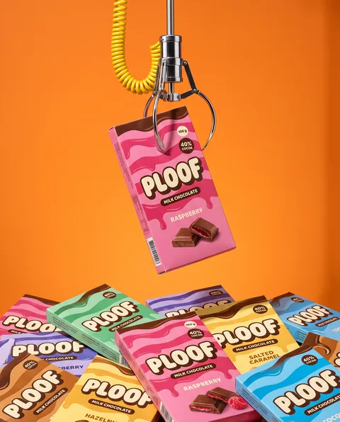 Ploof : pince de fête foraine attrapant une tablette de chocolat au-dessus d’un tas de boîtes colorées